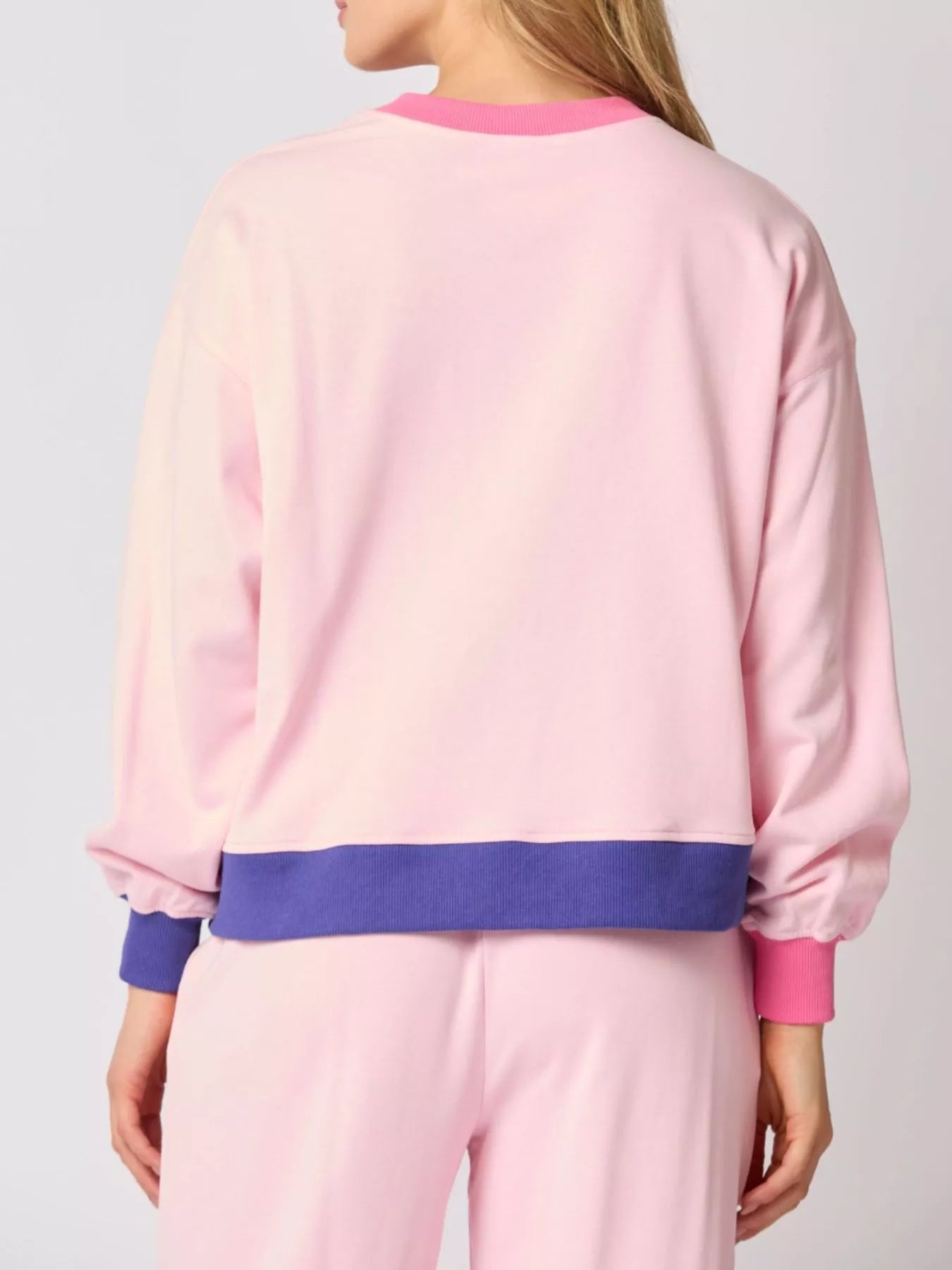 Person wearing a pink and purple outfit with a plain background