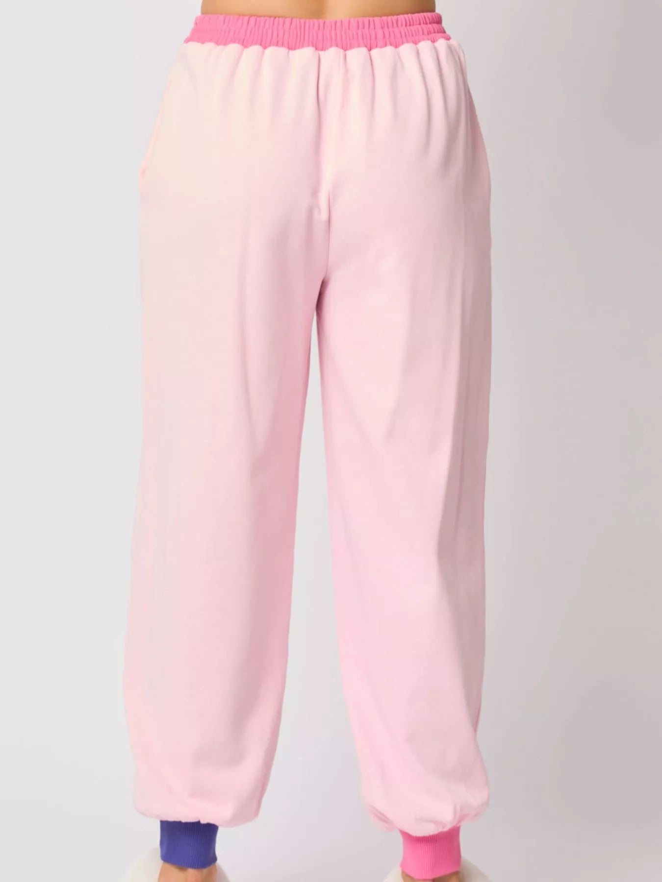 Pink sweatpants with a purple waistband on a light gray background