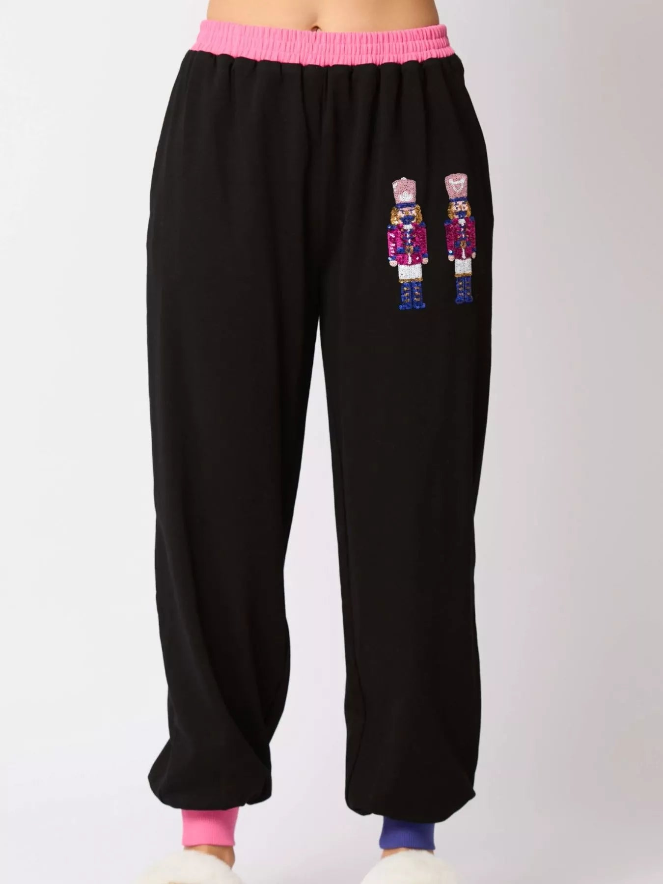 Black sweatpants with embroidered nutcrackers on a white background