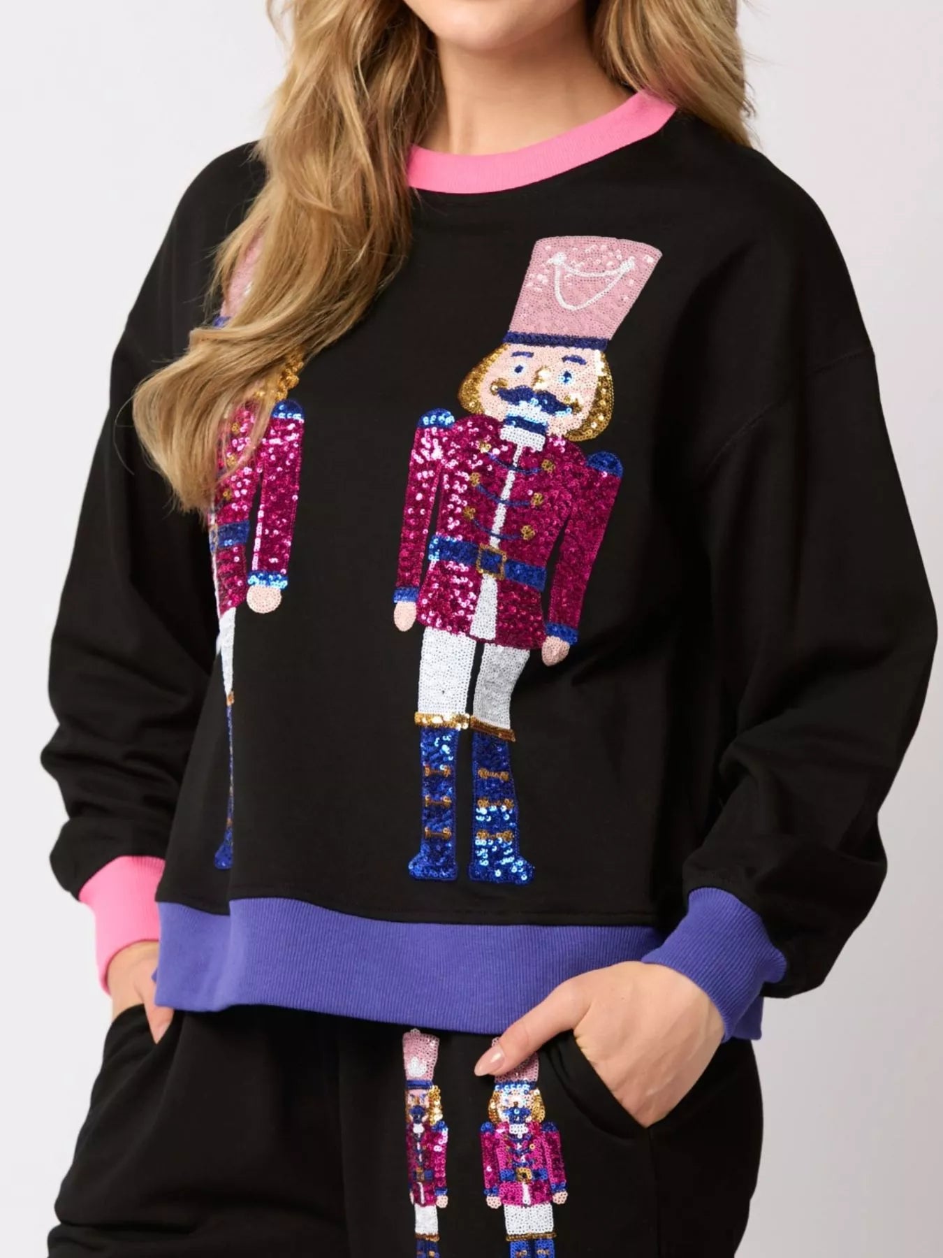 Black sweatshirt with colorful sequin nutcracker design on a plain background