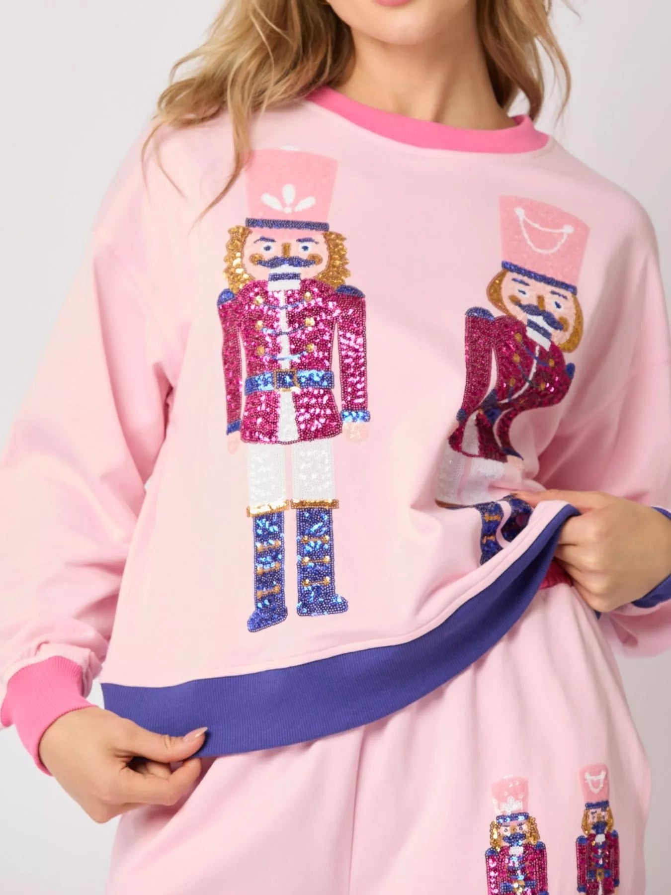 Pink sweatshirt with nutcracker designs held by a person