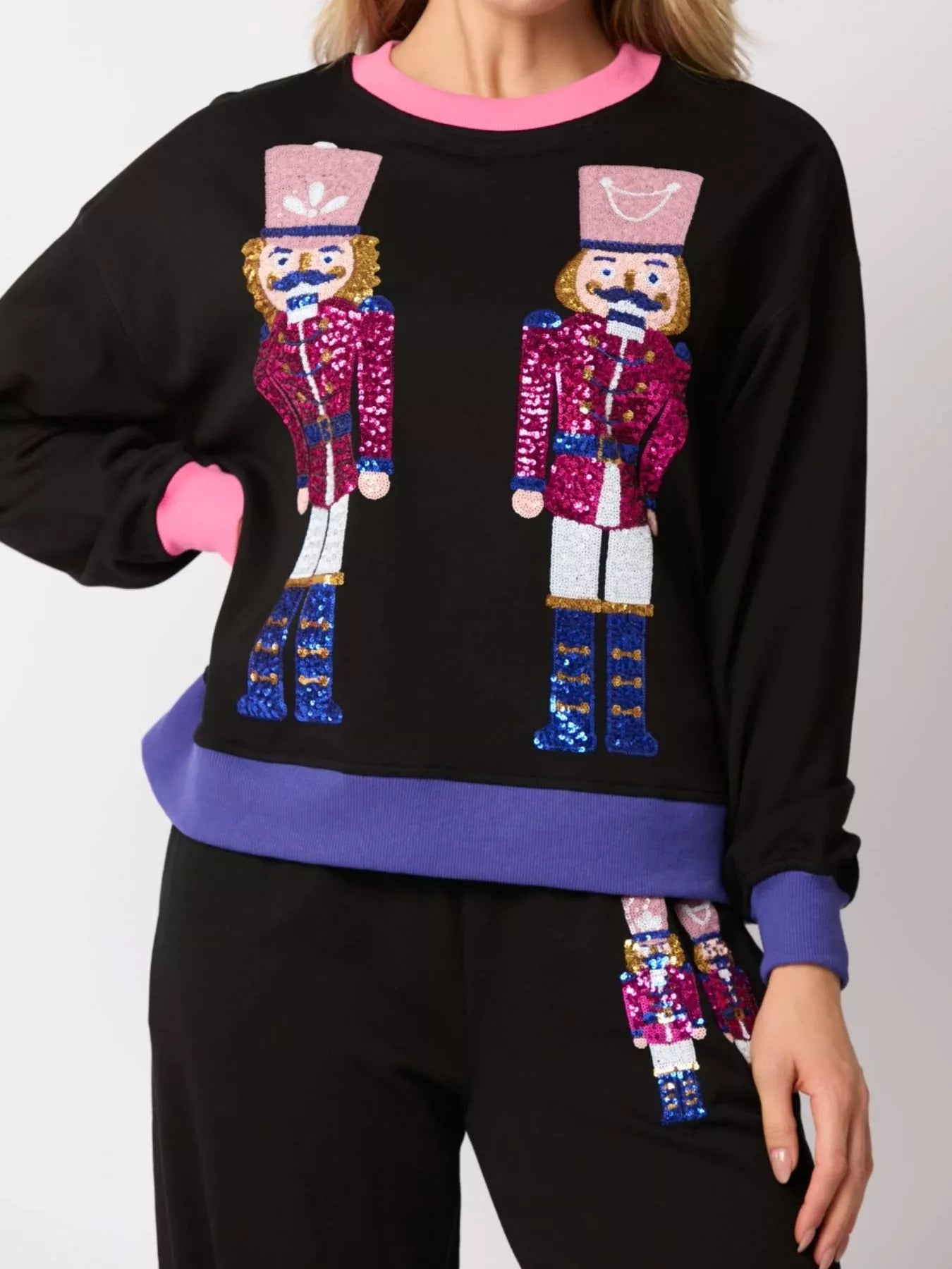 Black sweater with sequin nutcracker design on a plain background