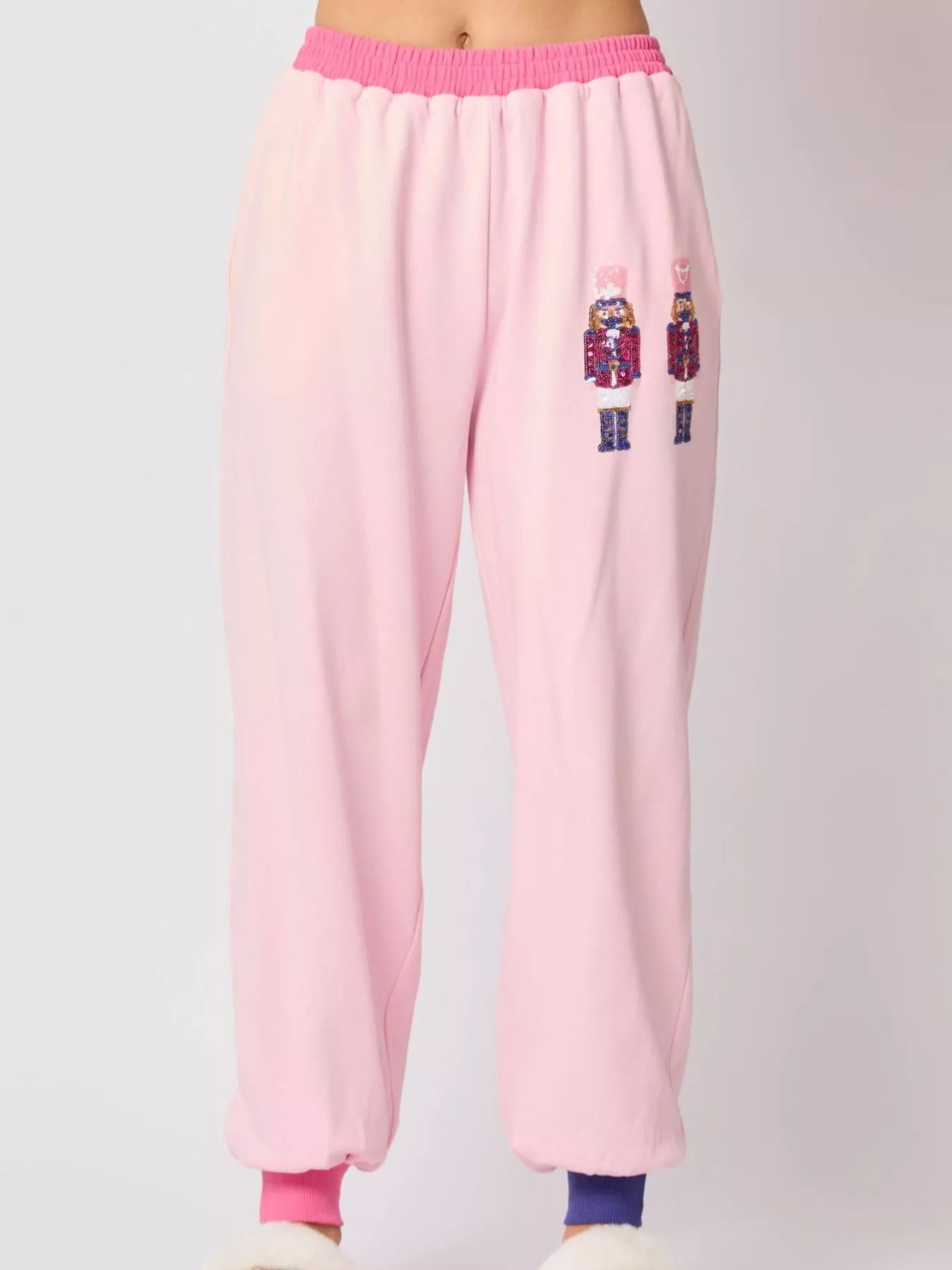 Pink sweatpants with embroidered designs on a light gray background